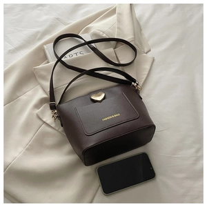 Détail du sac marron foncé avec verrou en métal en forme de cœur et texture de litchi