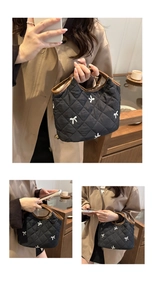 Detail of embroidered white bows on black quilted handbag with brown leather handles