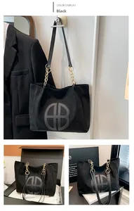 Detalle del bolso tote negro de antelina con logo HB de cuero y cadena de metal dorado