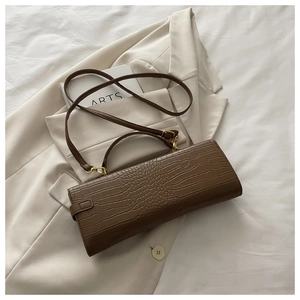 Detailed macro view of the dark brown crocodile pattern texture and gold hardware on bag