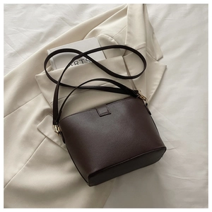 Vue de dessus d'un sac seau en cuir marron foncé avec détails dorés et bandoulière