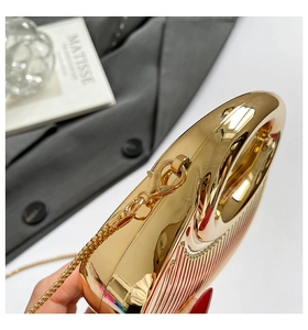 Detail of gold metallic clutch bag featuring vertical textured shell and fine chain strap