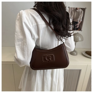 Detail of dark brown retro hobo bag featuring a G-embossed square logo and thin strap