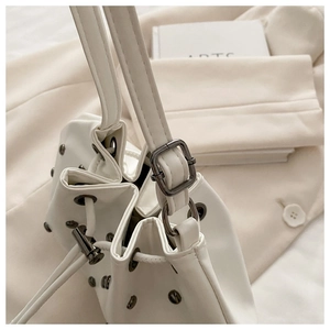 Detail of white bucket bag featuring silver rivets and adjustable silver-black buckle