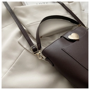 Détail du sac à bandoulière en cuir marron foncé avec fermoir doré en forme de cœur