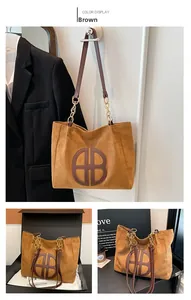 Detalle del bolso tote de ante marrón con logo BB, asa de cadena y embalaje de regalo