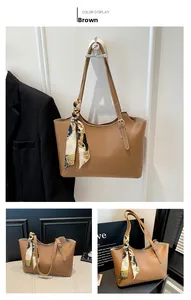 Brown tote bag detail with baroque silk scarf and adjustable strap on a neutral background