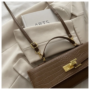 Macro view of brown crocodile texture leather bag with gold metal twist-lock detail