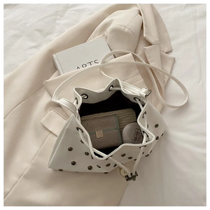 Internal view of cream drawstring bucket bag with rivets showing storage for essentials
