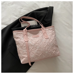 Detail of light pink pleated tote bag featuring delicate white floral embroidery patterns