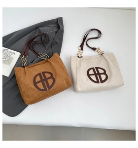 Détail d'un cabas en daim avec bandoulière en chaîne dorée et broderie logo BB