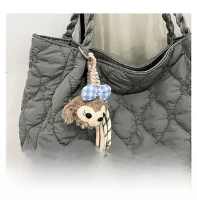 Detail of ShellieMay plush charm with blue bow attached to a gray quilted shoulder bag