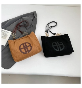 Détail du sac cabas en daim avec logo circulaire, chaînes dorées et style rétro