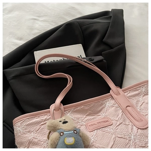 Detail of pink floral embroidery on large tote bag with a cute plush bear charm