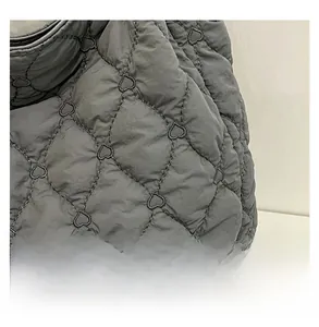 Macro detail of dark grey quilted nylon tote bag with unique heart-shaped stitching patterns