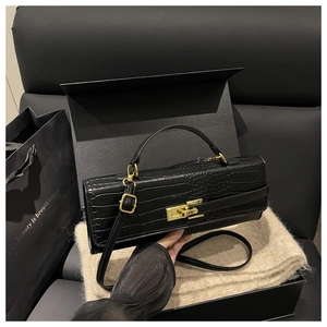 Detail of black crocodile pattern leather texture with gold-tone metal twist lock closure