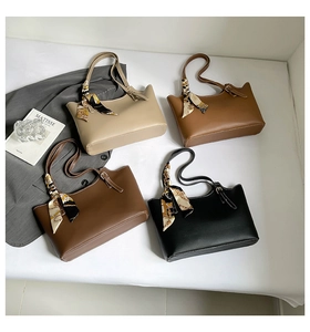 Close-up of stylish PU leather tote bags featuring wavy edges and decorative silk scarves