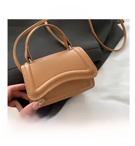 Detail shot of tan crossbody bag with unique curved flap and visible thick stitching