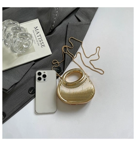Mini gold evening bag with vertical stripes and metallic chain on grey suit background