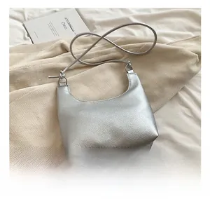 Detail of silver textured leather hobo bag with knotted strap on minimalist background