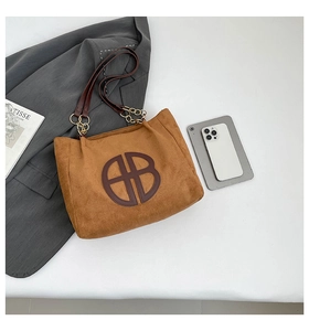 Sac cabas en daim marron avec détails découpés et bandoulière chaîne sur fond blanc