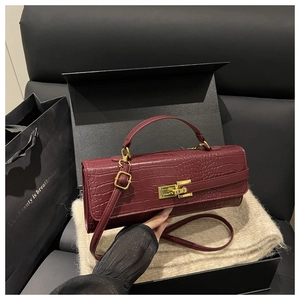 Close-up of wine red crocodile pattern leather bag with golden clasp on premium gift box