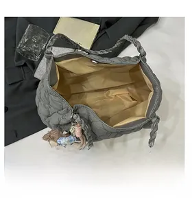 Close-up of gray quilted tote bag interior with yellow lining and plush bear charm