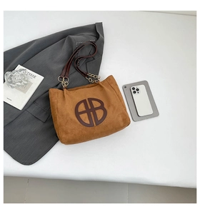 Détail du sac cabas en daim caramel avec logo BB en cuir et bandoulière dorée
