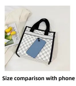 Size comparison of white printed tote bag with a smartphone on a white surface