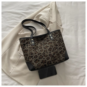 Detail view of leopard print tote bag featuring leather handles and gold stud accents