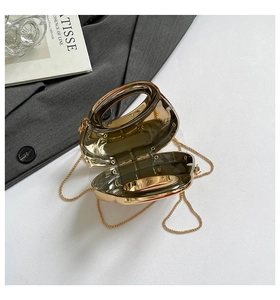 Close-up of golden irregular metal evening bag with grey acrylic insert and chain strap