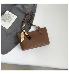 Close-up of brown leather tote bag with printed silk scarf on a stylish white desk