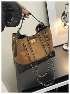 Close-up of brown suede and black patent leather tote bag with gold chain strap