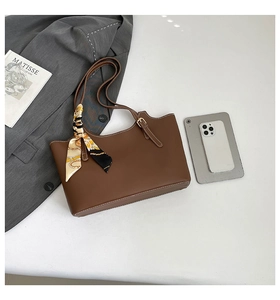 Detail of dark brown tote bag with white contrast stitching and decorative silk scarf