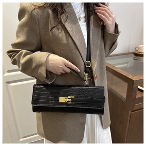 Close-up of black crocodile pattern faux leather handbag with elegant gold metal twist lock