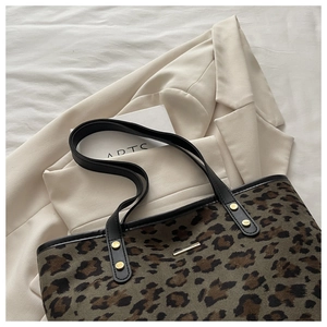 Detailed view of leopard print tote bag with black leather straps and gold metal hardware