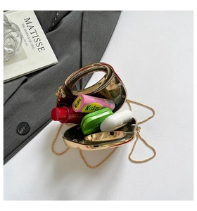 Detailed view of an open golden hard-shell evening bag with chic metal oval handle and chain