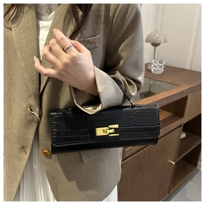 Close-up of black crocodile pattern baguette bag with a golden turn-lock closure