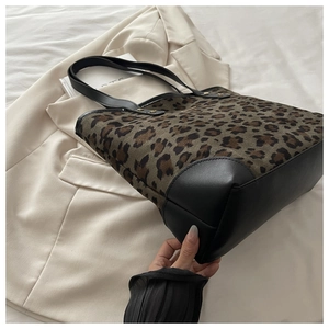 Detailed close-up of leopard print fabric and black leather trim on a large tote bag