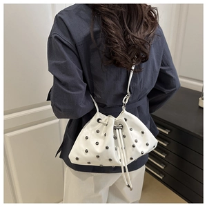 Detail view of white leather bucket bag with silver studs and drawstring closure