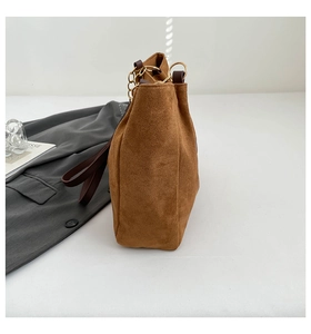 Détail du sac bandoulière en daim marron avec anneau doré et texture plissée latérale