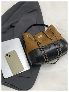 Detail of color-block quilted bag with gold twist lock and chain strap on grey blazer