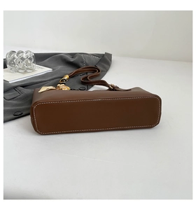 Detail of brown tote bag with white contrast stitching and floral scarf handle