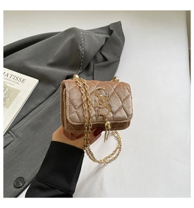 Détail macro du mini sac matelassé en velours champagne avec chaîne et boucle dorée