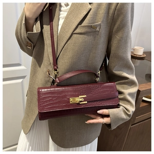 Macro detail of wine red crocodile embossed texture with golden twist lock on handbag