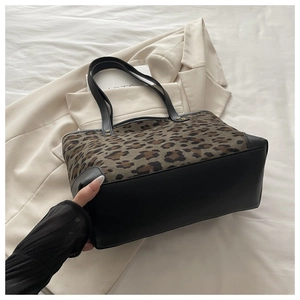 Close-up of leopard print tote bag with black leather straps and premium canvas texture