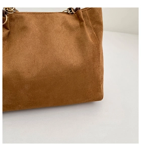 Détail d'un sac cabas en daim marron caramel avec texture douce et boucle en métal doré