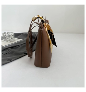 Detail view of brown leather tote bag with a silk scarf wrapped around the handle strap