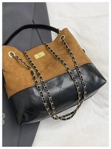 Detail of contrast stitching, brown suede texture and golden metal twist lock on the bag