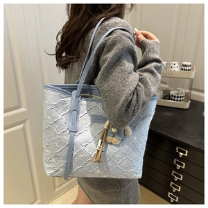 Detail of light blue tote bag featuring embossed texture and white flower embroidery